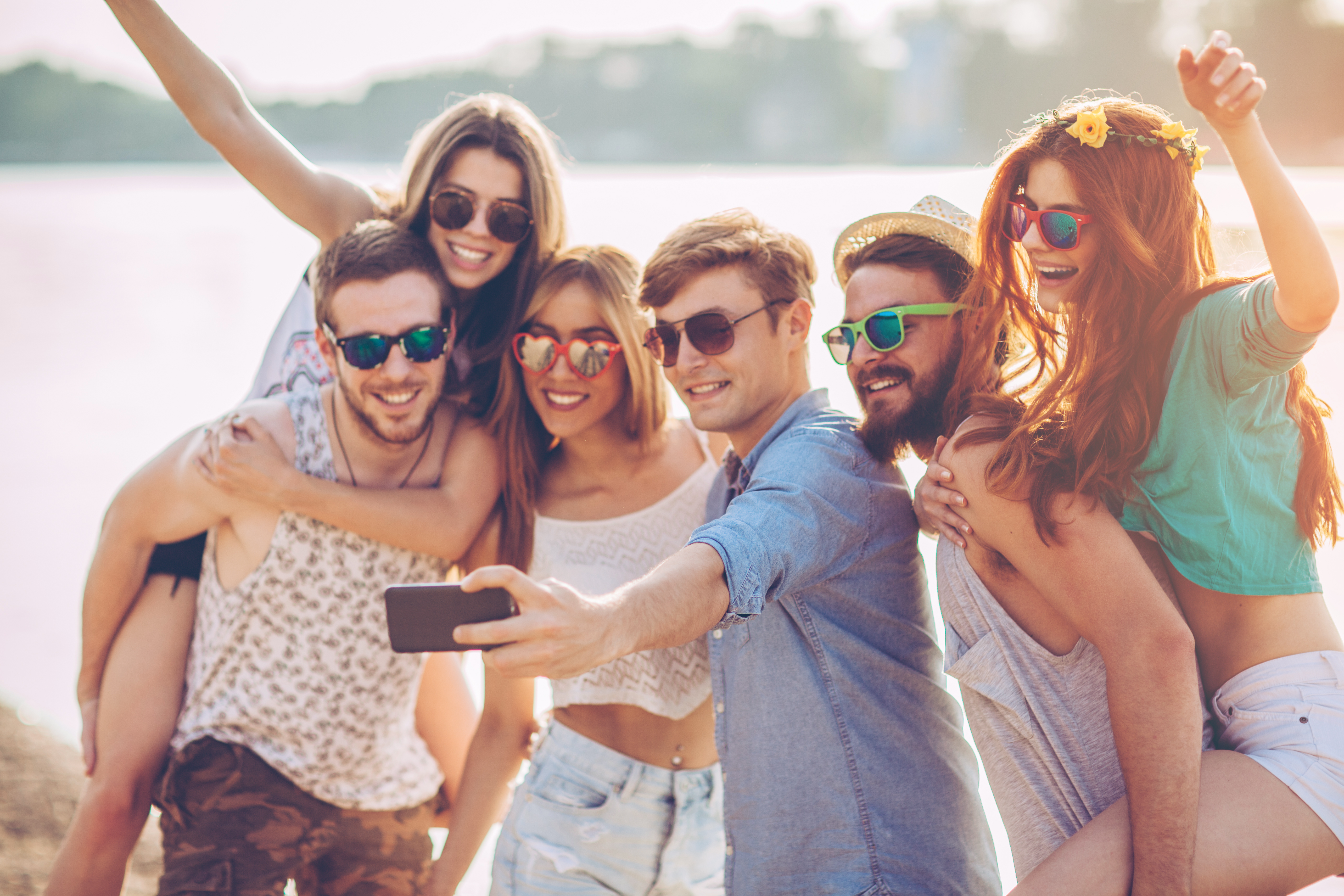 Group of young people on the beach having party. Takin selfie and dancing. They are happy and joyful. Sunny day.
